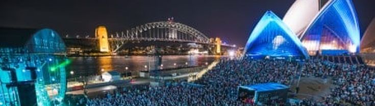 Image of concert in front of a lit-up Sydney Opera House at nighttime